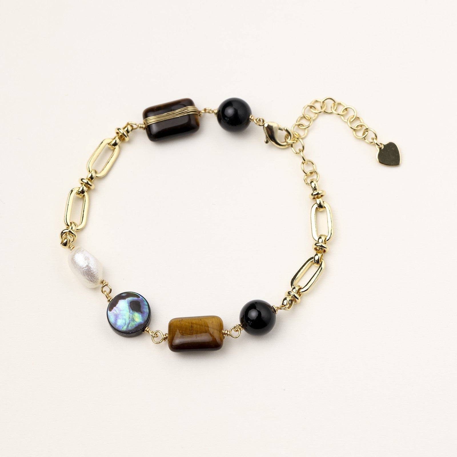 Gold-plated chain bracelet featuring tiger's eye, obsidian, freshwater pearls and abalone shell on white background
