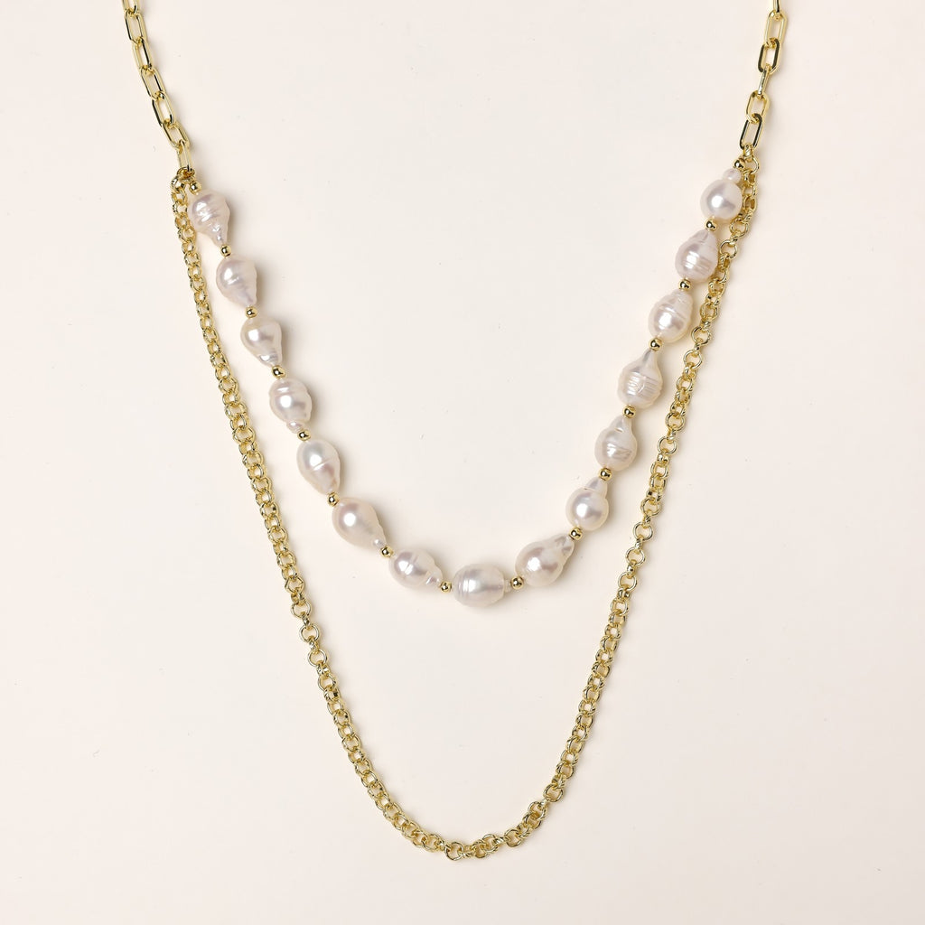 Layered gold chain necklace with irregular freshwater pearls on cream background, showing adjustable dual-strand design.