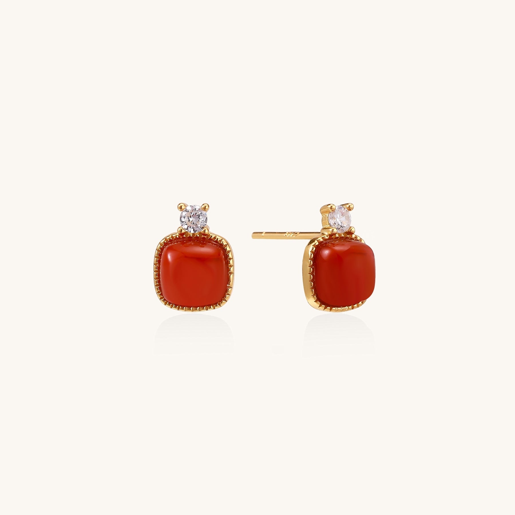 Gold-plated sterling silver stud earrings with square south red agate stones and clear crystals on cream background