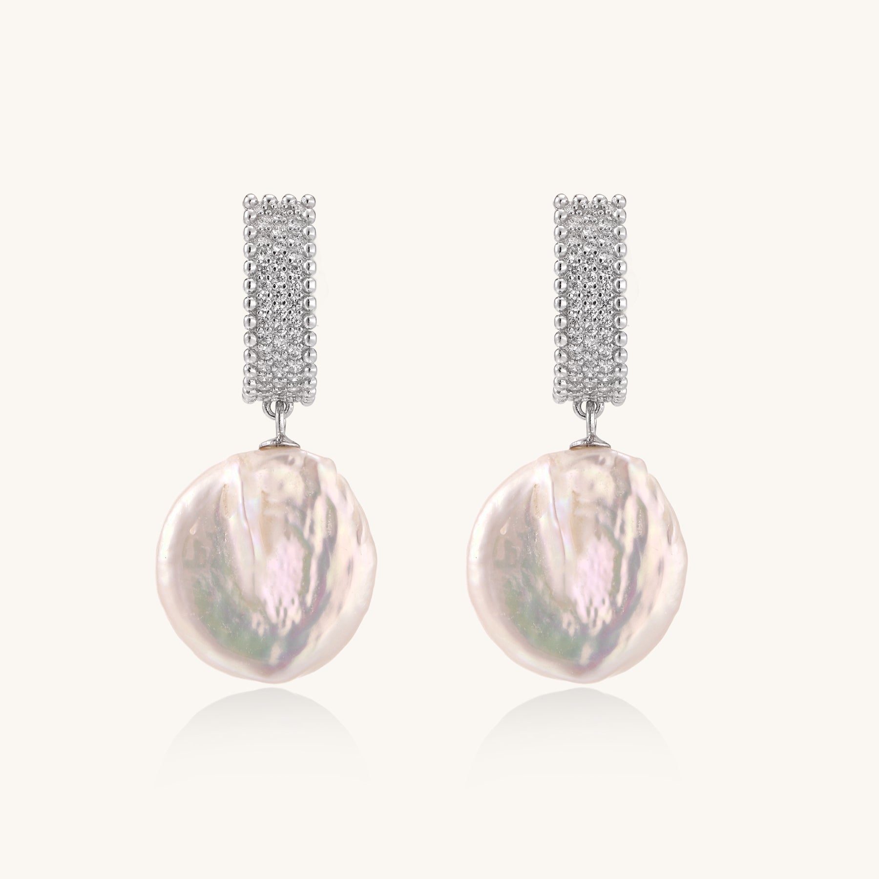 Sterling silver huggie earrings with lustrous baroque pearls displaying iridescent pink and cream tones on white background.