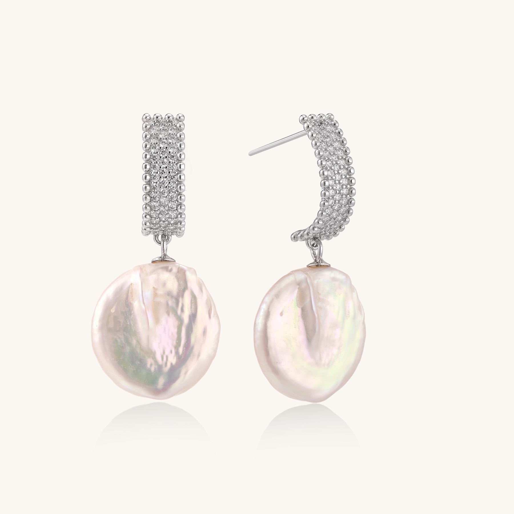 Sterling silver huggie earrings with lustrous baroque pearls displaying iridescent pink and cream tones on white background.
