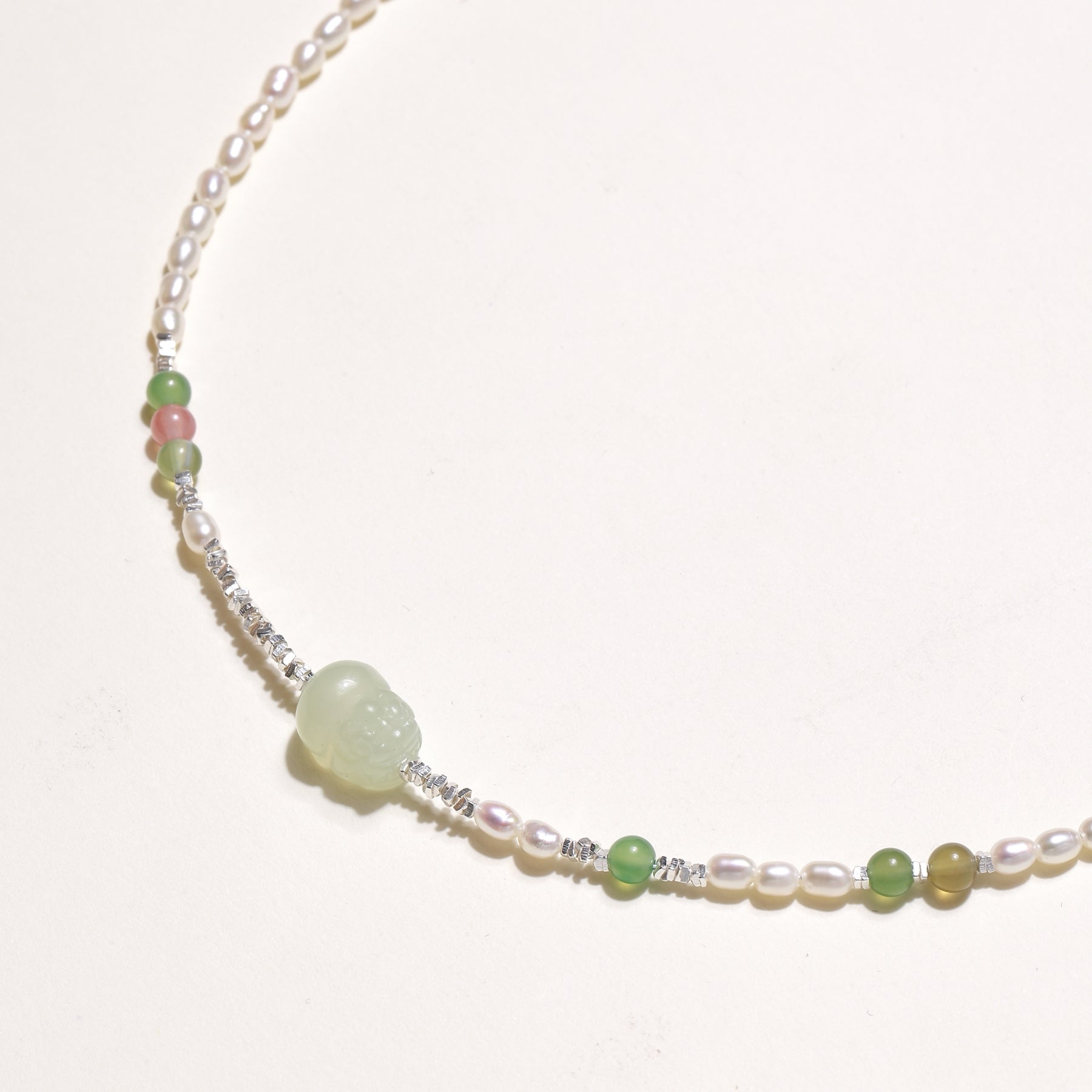 Delicate sterling silver necklace with freshwater pearls, green serpentine centerpiece, and mixed agate beads on white background.