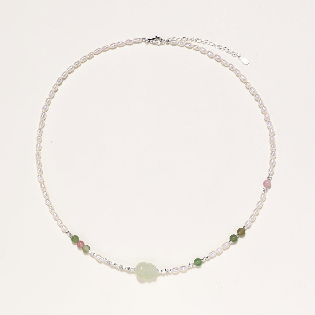 Delicate sterling silver necklace with freshwater pearls, green serpentine centerpiece, and mixed agate beads on white background.