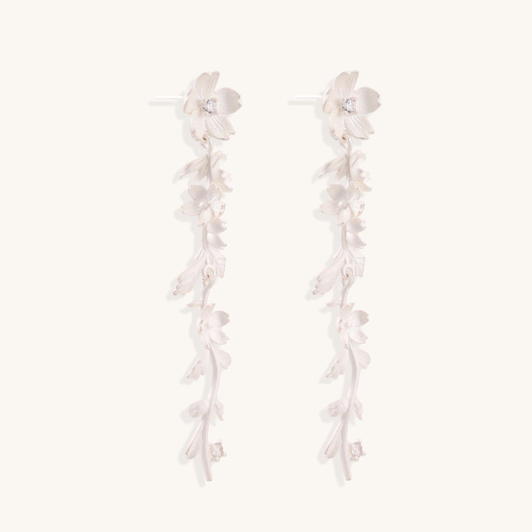 Pair of sterling silver dangle earrings with intricate leaf vine patterns and crystal accents on white background.