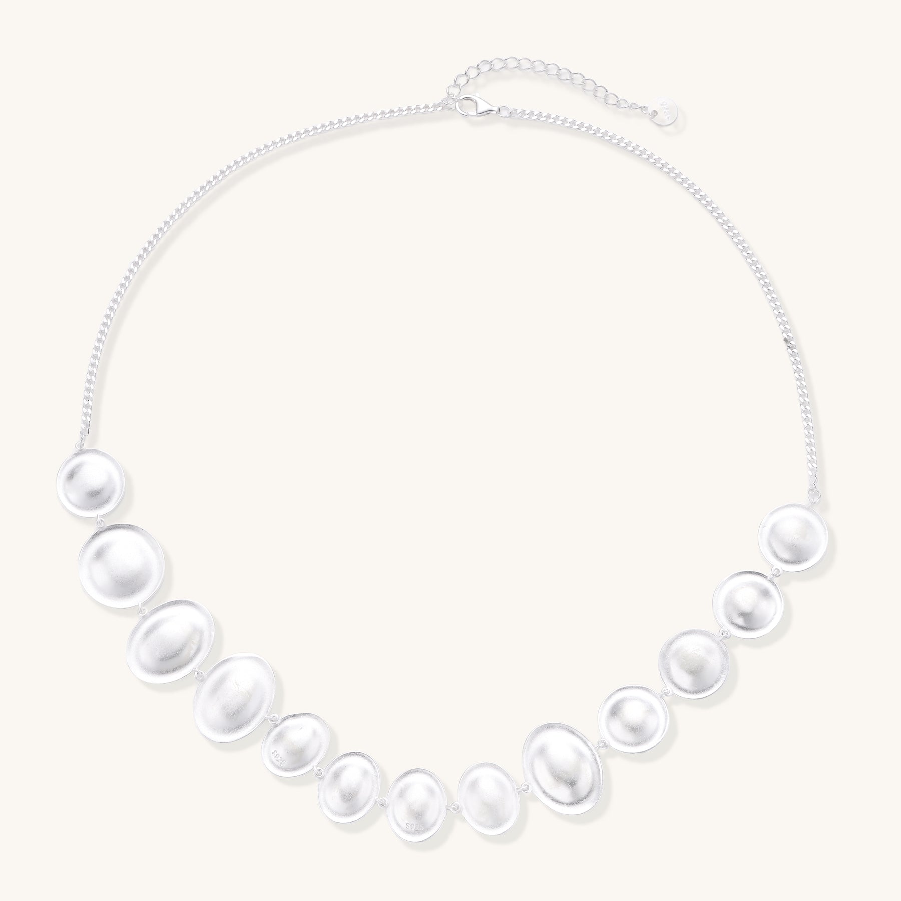 Sterling silver necklace with asymmetrically placed white pearls of varying sizes on neutral background