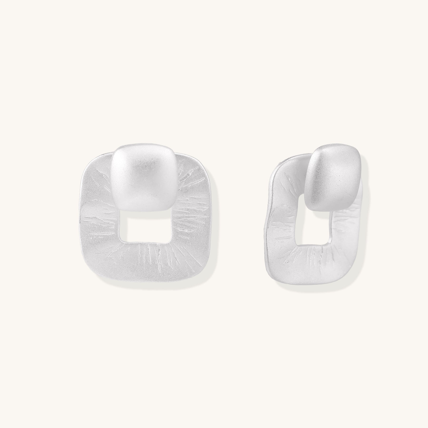 Geometric sterling silver square stud earrings with brushed texture and central square cutouts on white background.