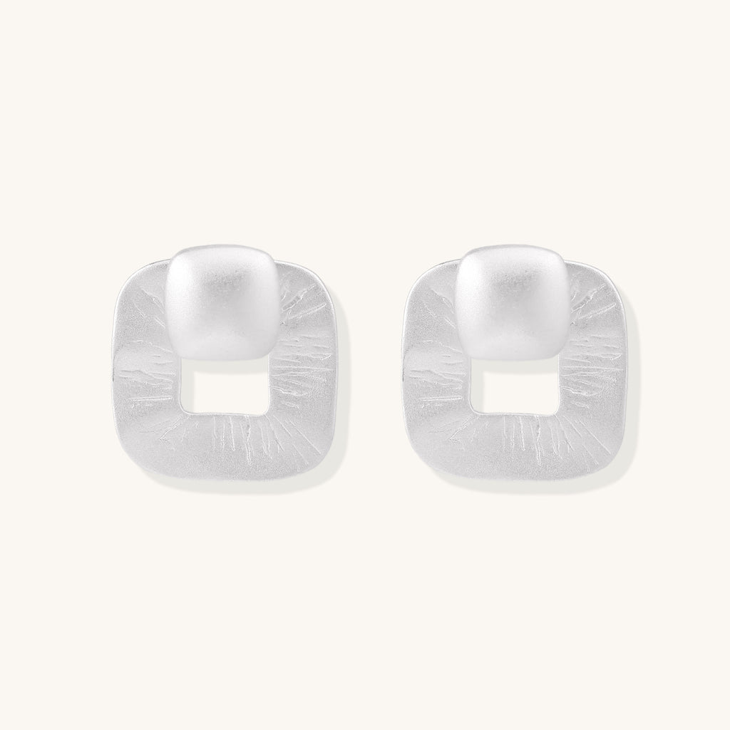 Geometric sterling silver square stud earrings with brushed texture and central square cutouts on white background.