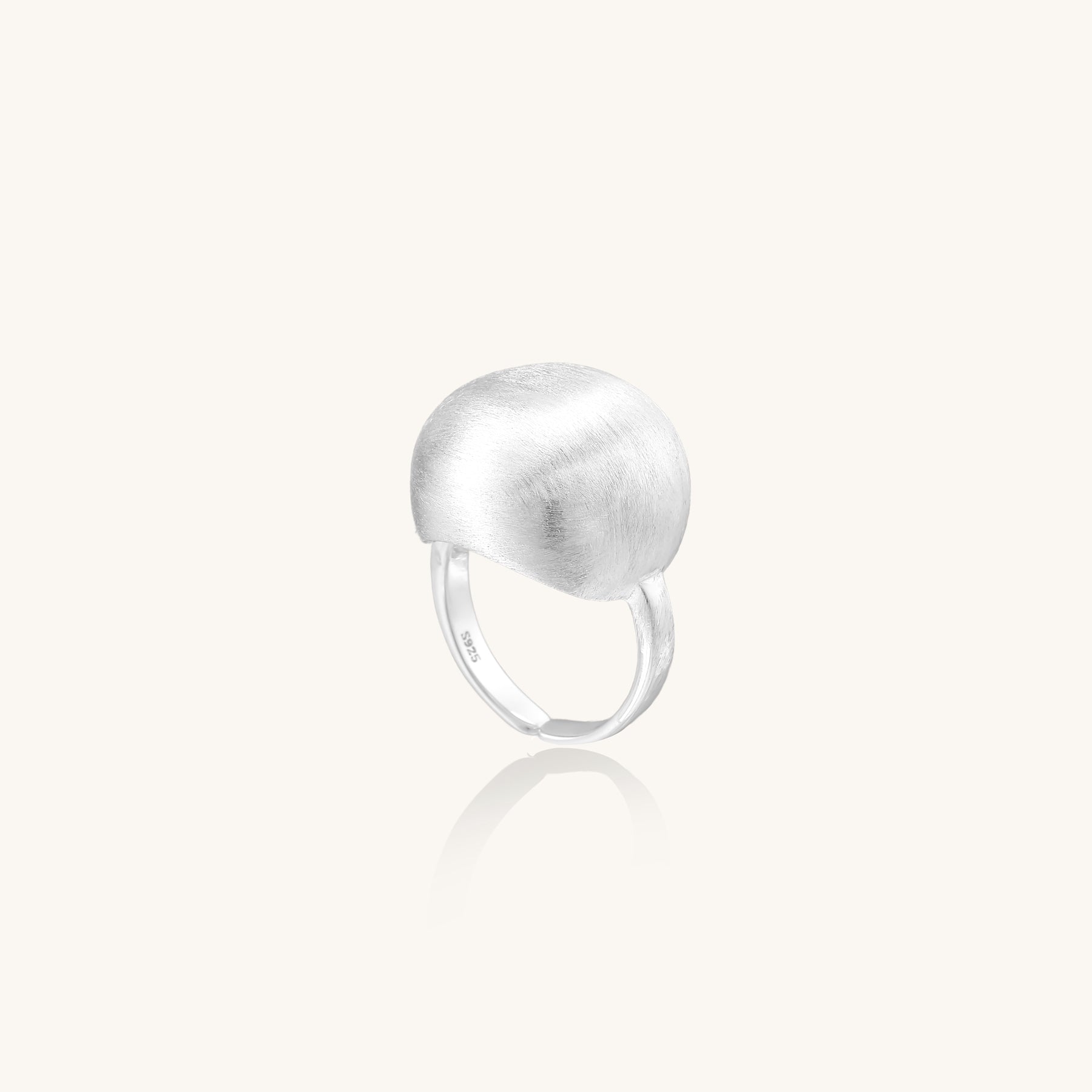 Minimalist sterling silver ring with large brushed disc top and adjustable band on white background.