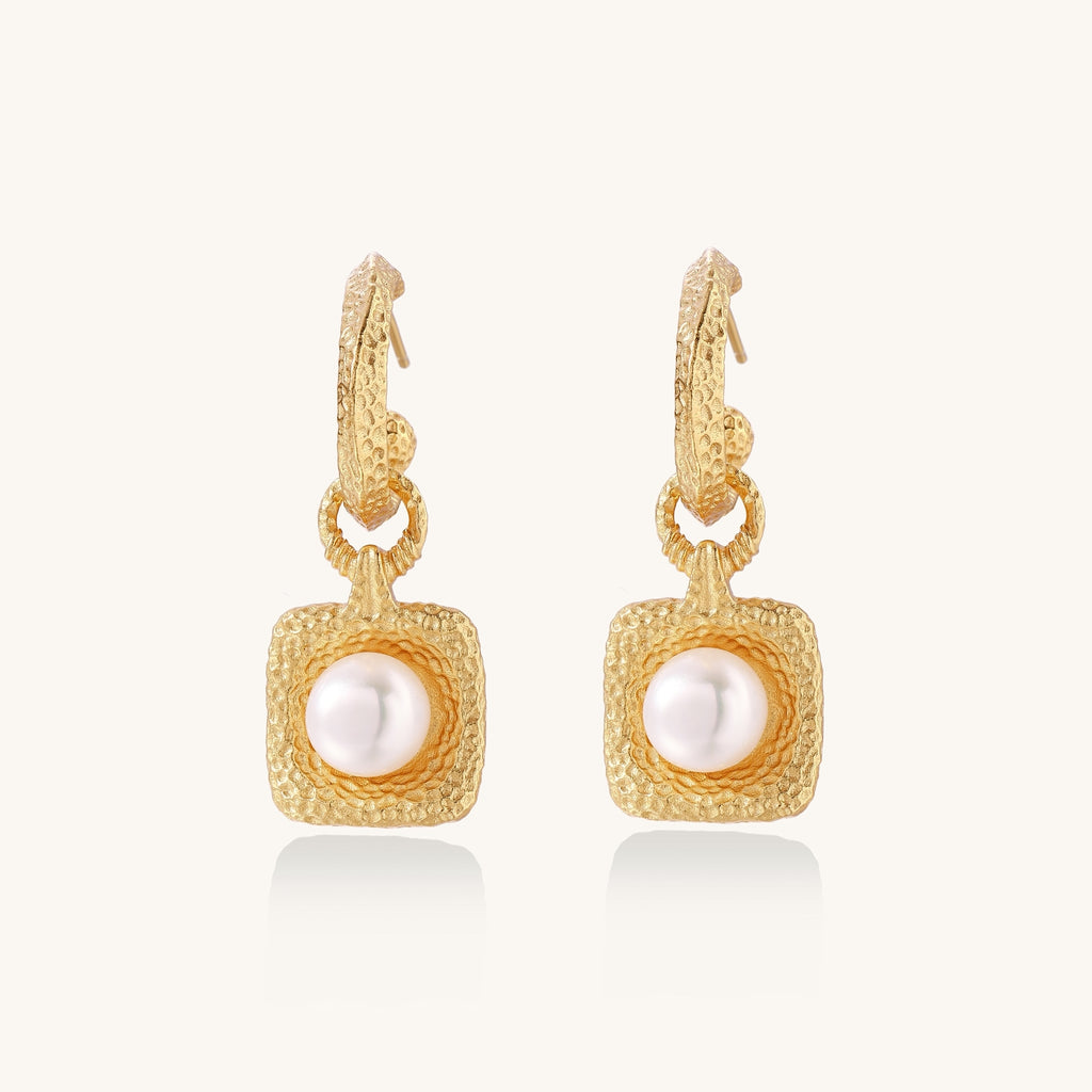 Gold-plated textured hoop earrings with square pendants containing freshwater pearls on white background