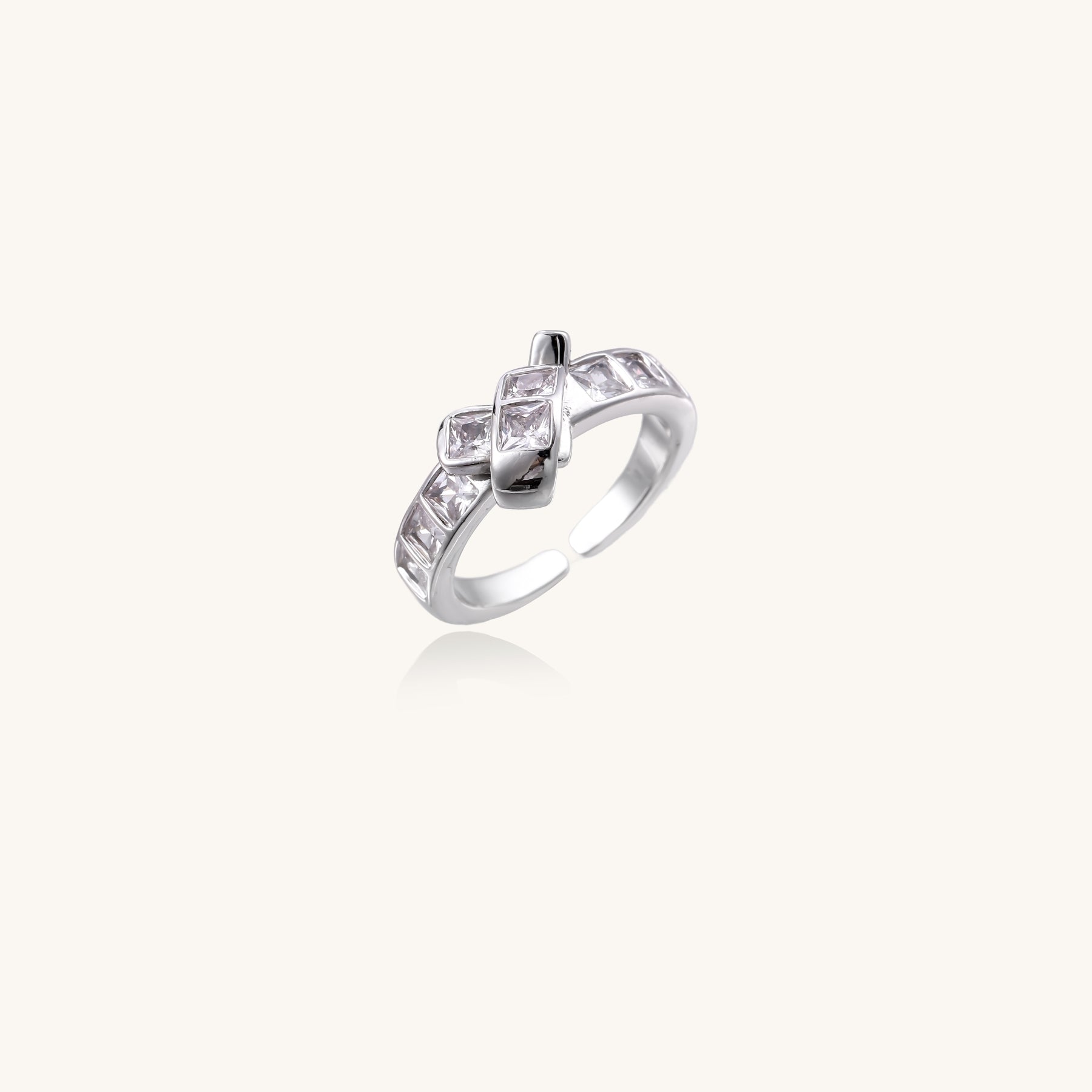 Close-up of geometric gold-plated brass ring with square-cut zirconia stones in architectural tiered design on white background.