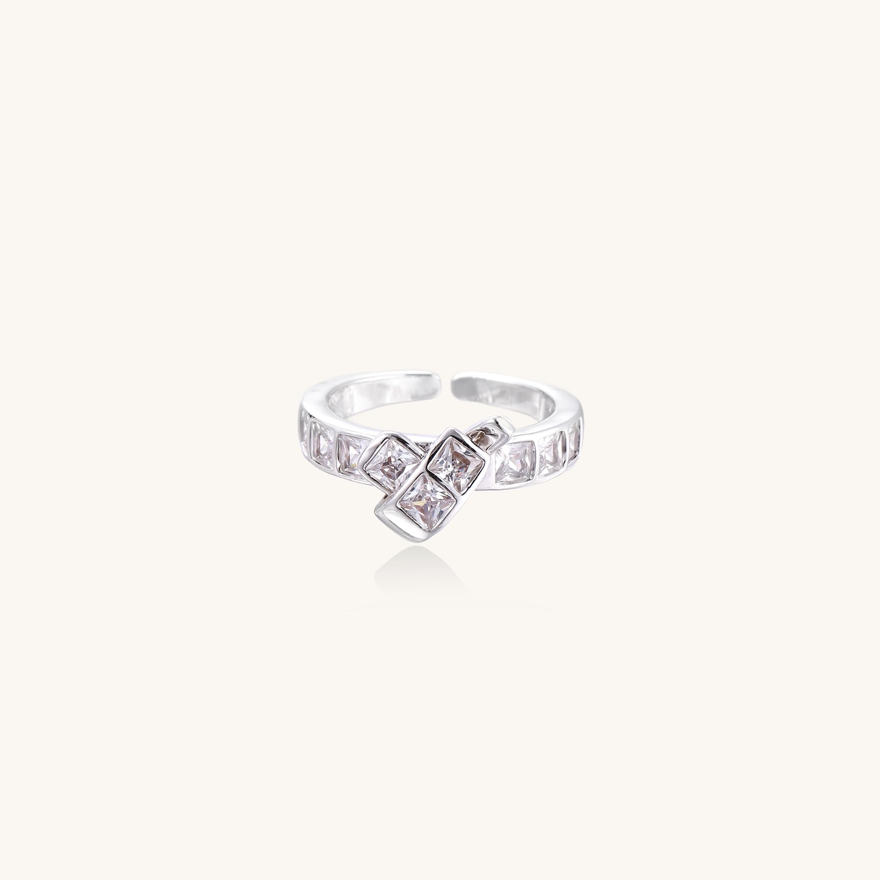 Close-up of geometric gold-plated brass ring with square-cut zirconia stones in architectural tiered design on white background.