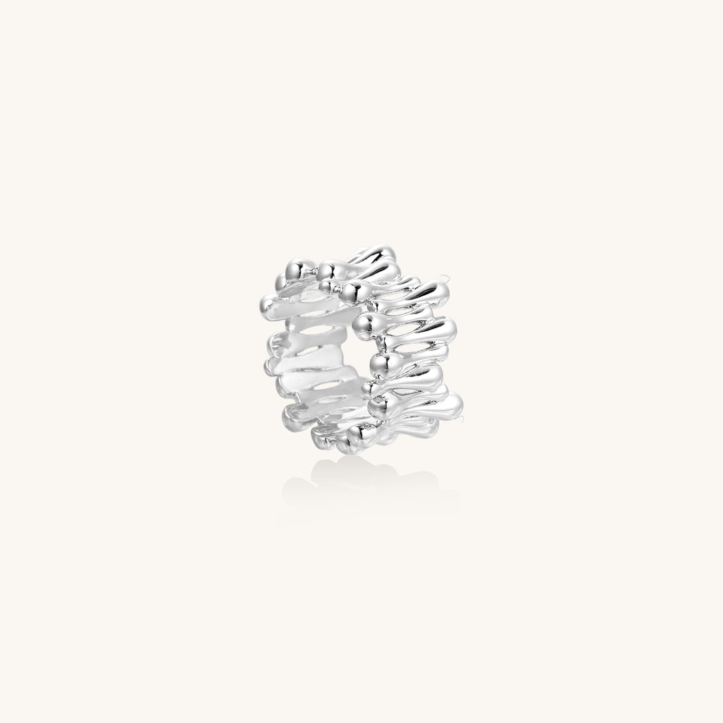 Close-up of an artistic gold-plated brass ring with multiple twisted bands creating a sculptural flowing design
