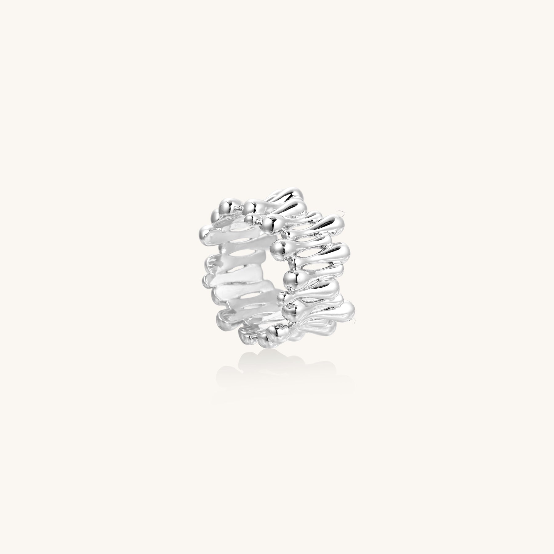 Close-up of an artistic gold-plated brass ring with multiple twisted bands creating a sculptural flowing design