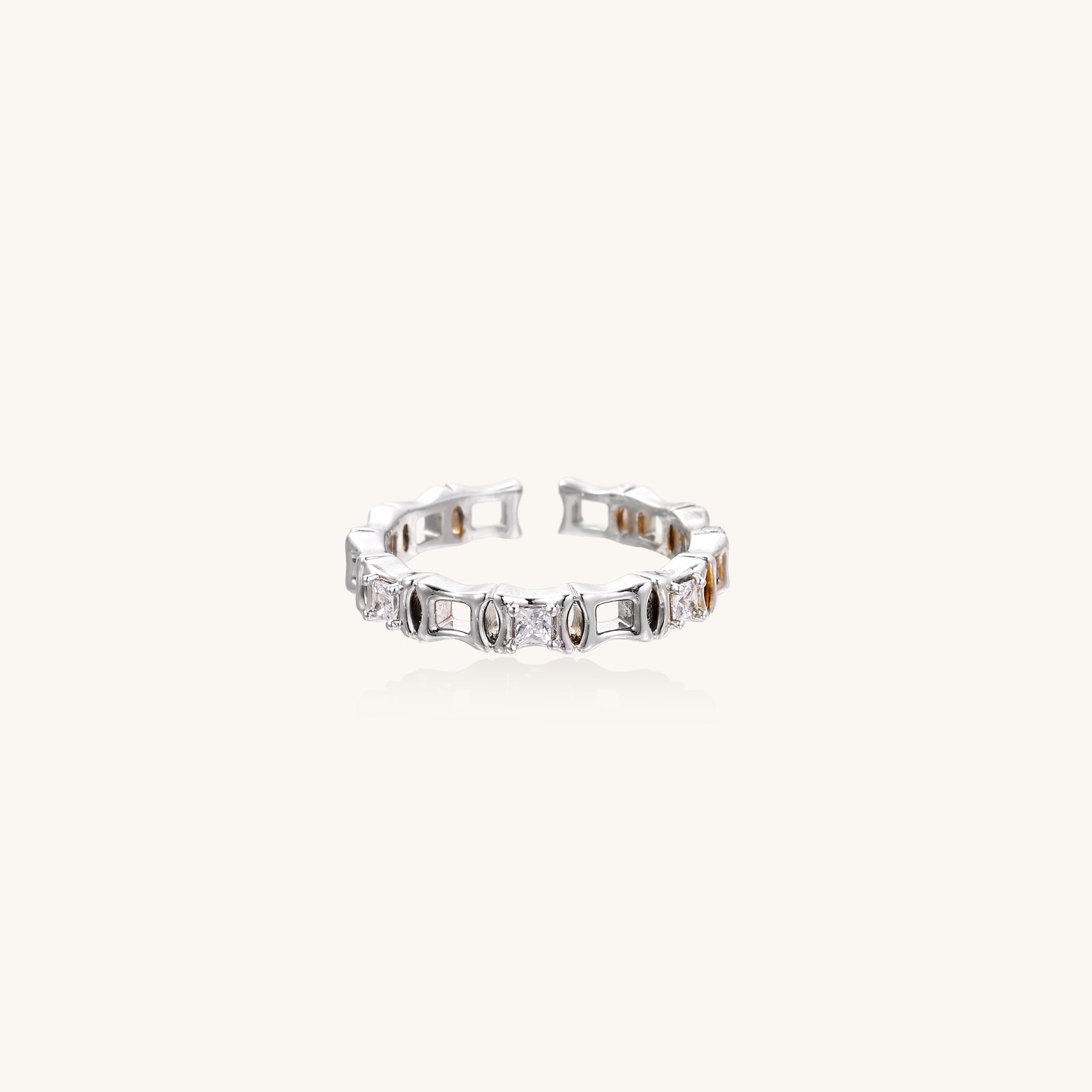Close-up of geometric gold-plated ring with alternating rectangular blocks and zirconia crystals on white background.