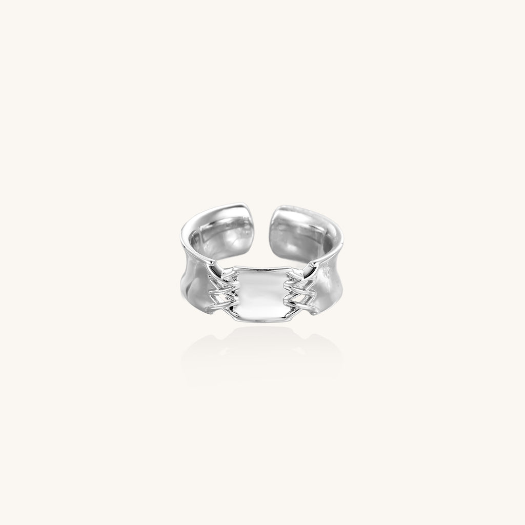 Chunky gold plated brass cuff ring with chain link details connecting two wide bands on neutral background.
