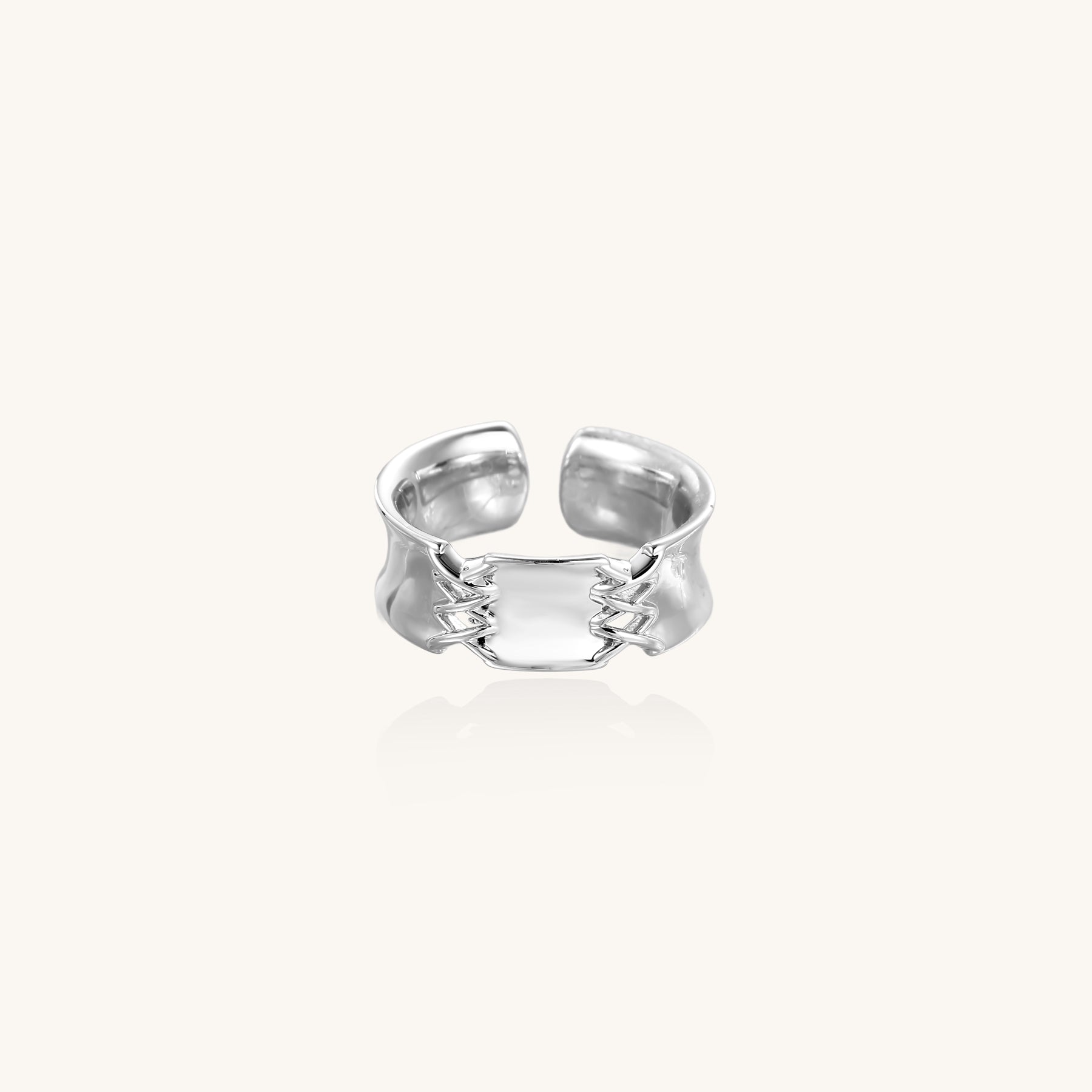 Chunky gold plated brass cuff ring with chain link details connecting two wide bands on neutral background.