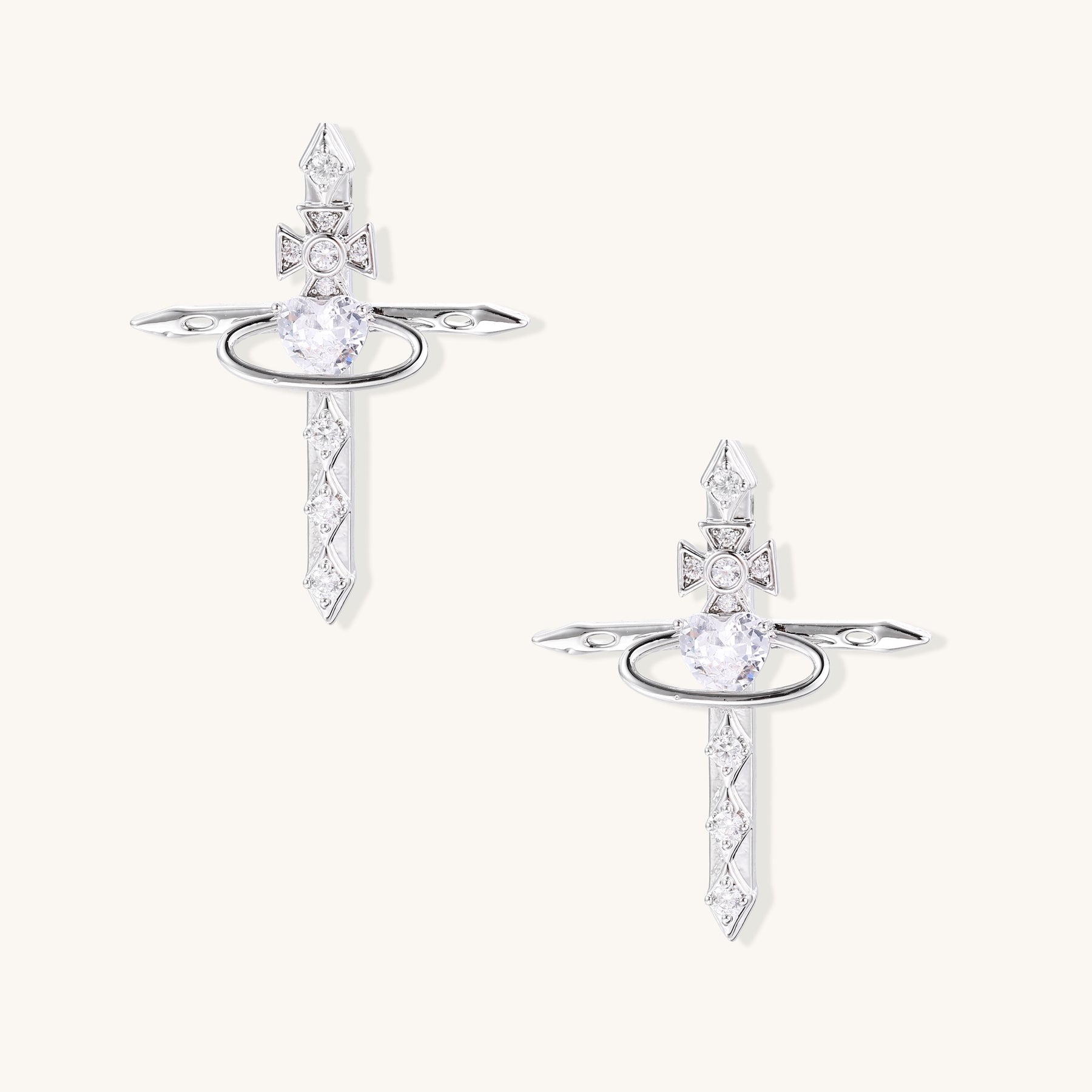 Gold-plated dangle earrings with cross tops, oval halos, and pointed bottoms adorned with clear zirconia stones
