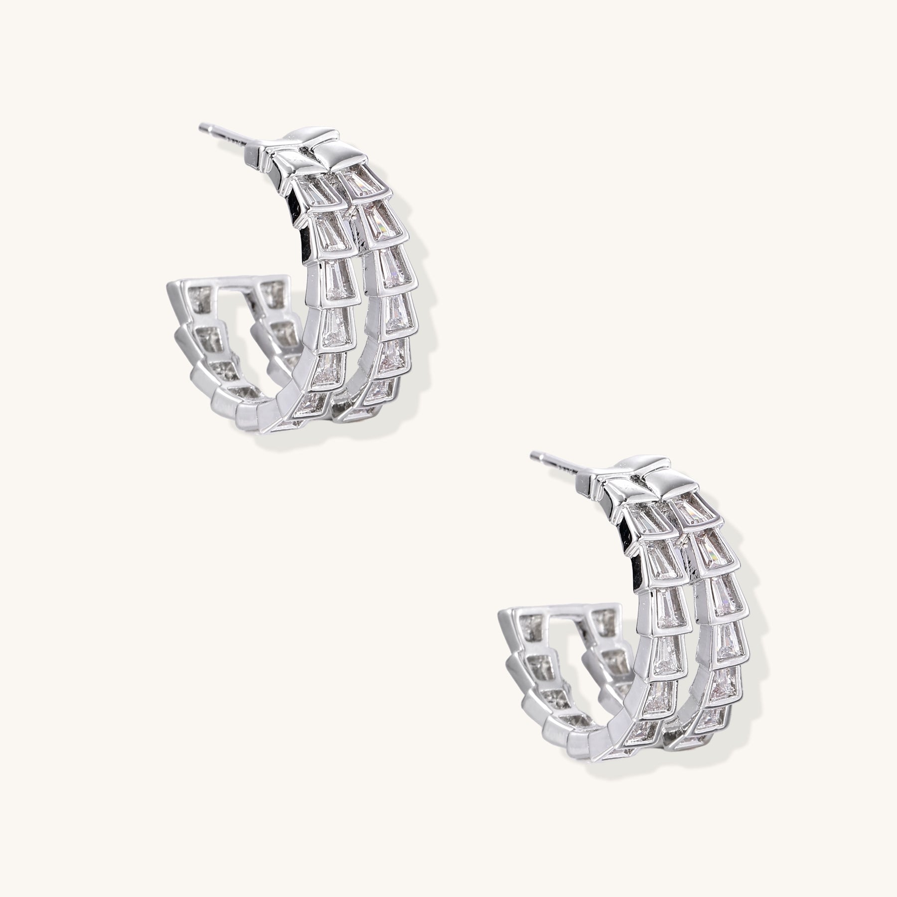 Gold-plated huggie hoops featuring vertical rows of clear baguette zirconia stones in geometric linear design