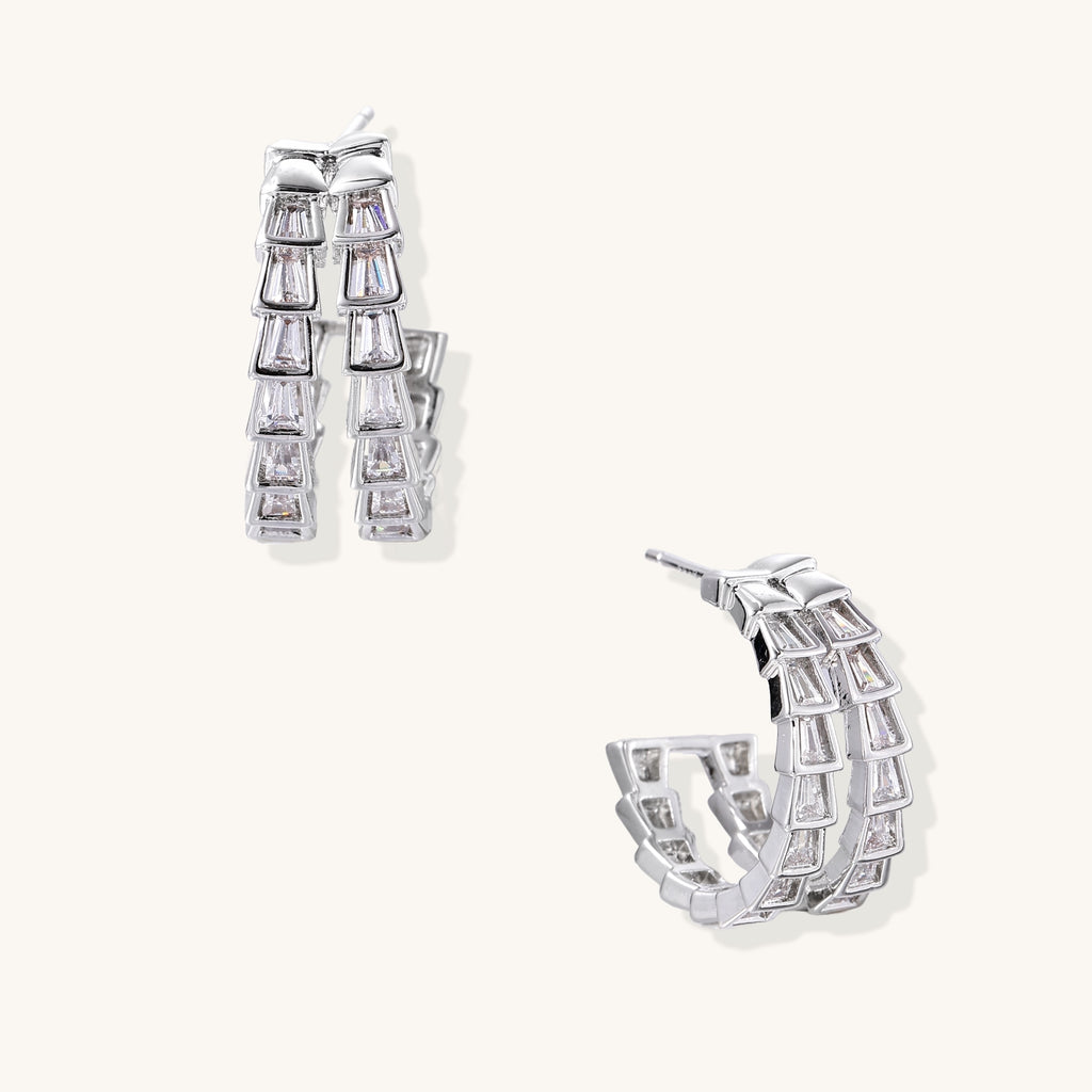Gold-plated huggie hoops featuring vertical rows of clear baguette zirconia stones in geometric linear design