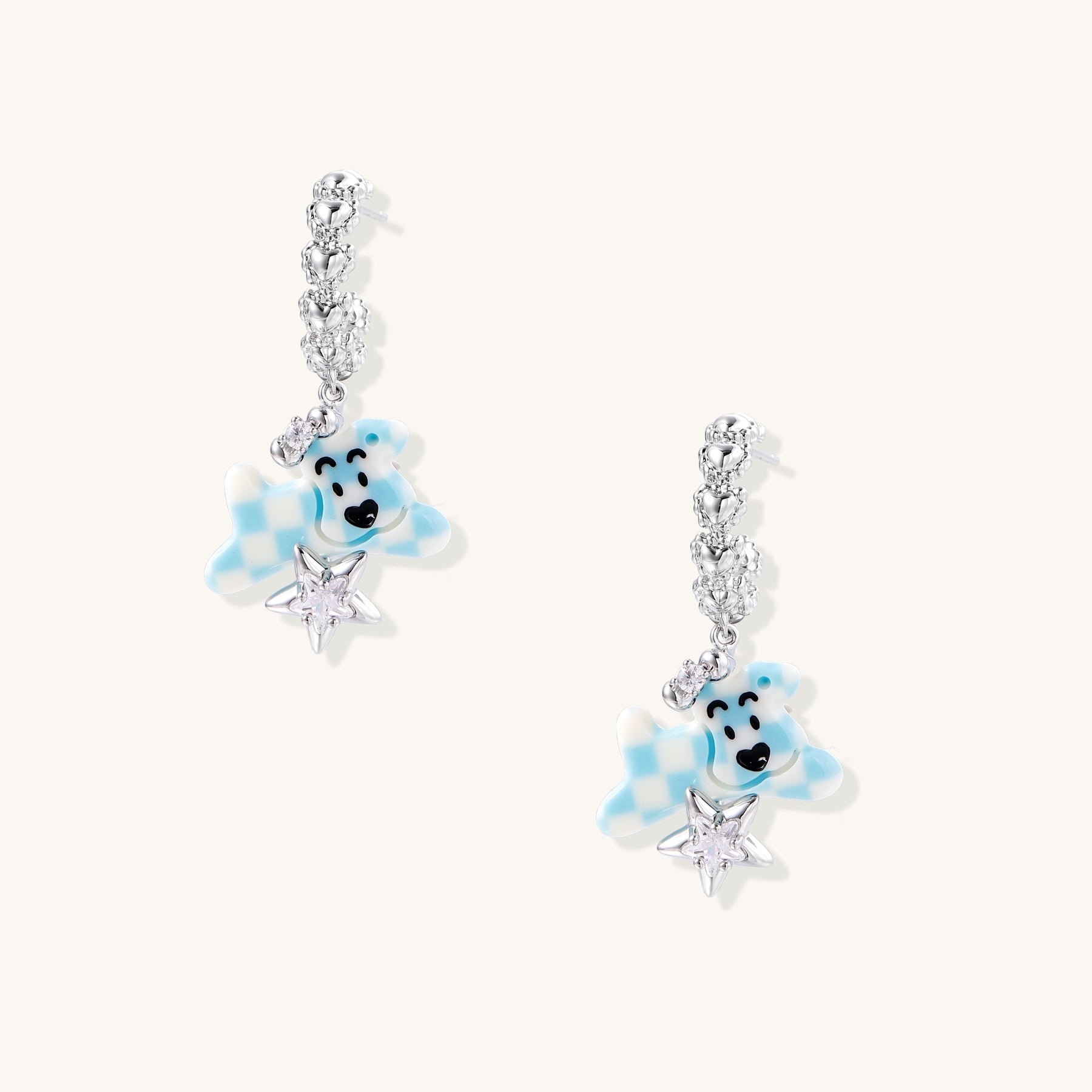 Dangle earrings with crystal chain and blue teddy bear charms holding silver stars, 18K gold plated brass construction.