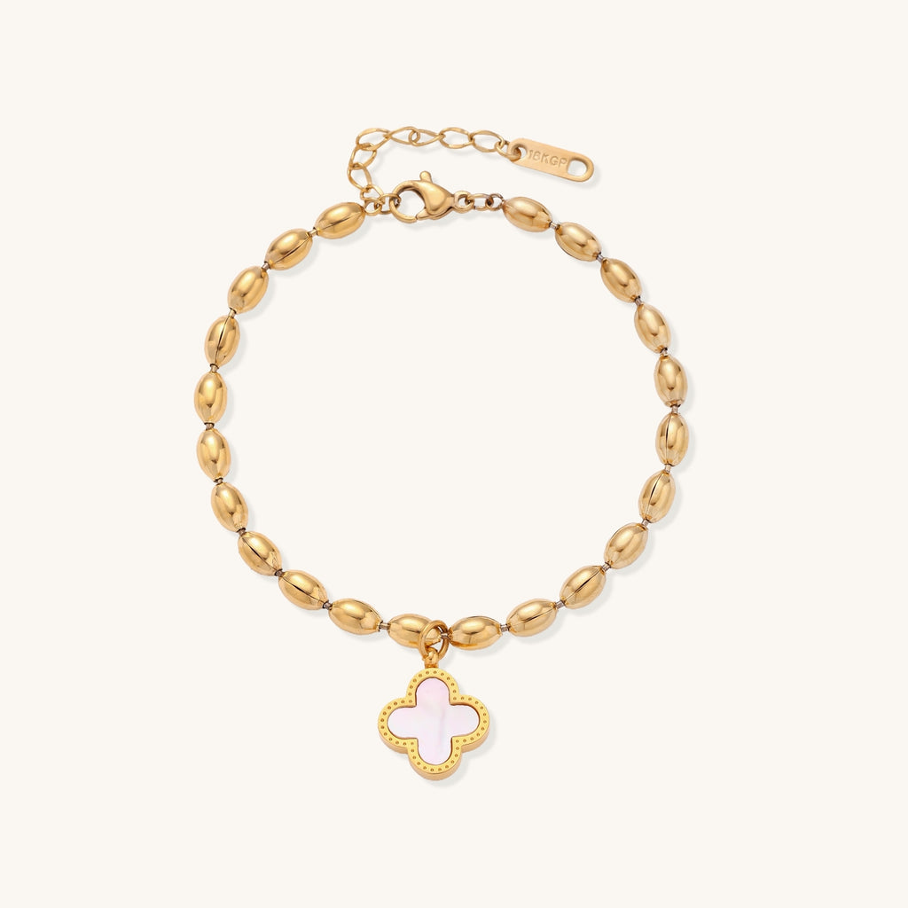 Dainty gold-plated beaded bracelet with oval links and four-leaf clover charm pendant on neutral background.