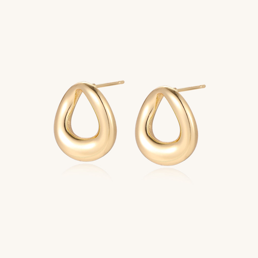 Pair of polished 18K gold-plated stainless steel oval loop stud earrings on cream background
