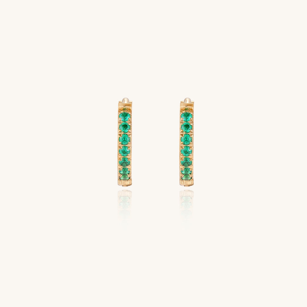 Small gold-plated huggie hoop earrings with emerald green cubic zirconia stones, one open showing hinge mechanism