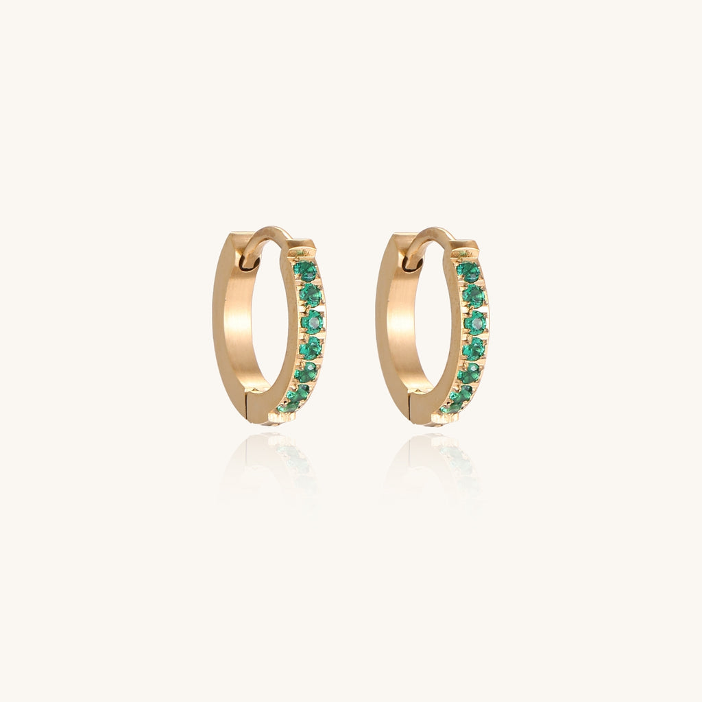 Small gold-plated huggie hoop earrings with emerald green cubic zirconia stones, one open showing hinge mechanism