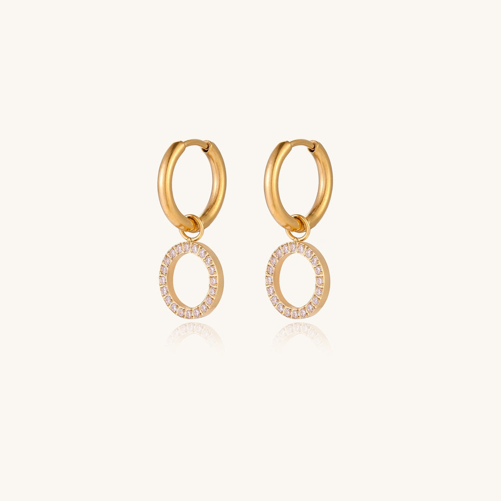 Gold-plated hoop earrings with circular cubic zirconia charm dangles displayed on neutral background.