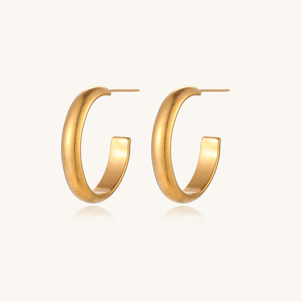 Four pairs of gold-plated stainless steel earrings including hoops and studs displayed on cream background