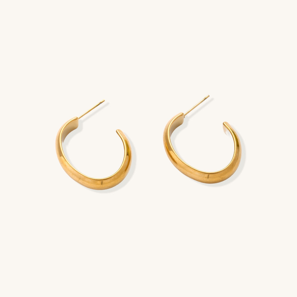 Four pairs of gold-plated stainless steel earrings including hoops and studs displayed on cream background